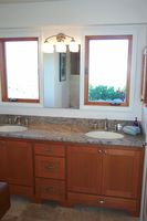 Thumb vanity  shaker style  cherry  recessed panel  light color  split panel  arched toekick  drawer bottom of sink section  standard overlay
