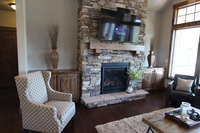 Thumb great room  traditional style  knotty alder  dark color  raised panel  base cabinets with wood tops  tv above fireplace  square mantel and corbels  entertainment center  standard overlay