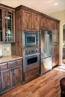 Thumb kitchen  traditional style  knotty alder  dark color  raised panel  double panel doors on the pantry  oven next to refrigerator  standard overlay