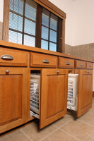 Thumb laundry or utility  craftsman style  quartersawn oak  raised panel doors with bevel drawer fronts  medium color  pull out hampers  standard overlay